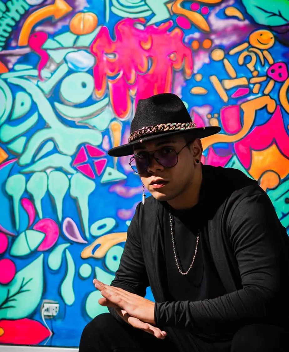 Fran Pérez con sombrero frente a un colorido mural de graffiti